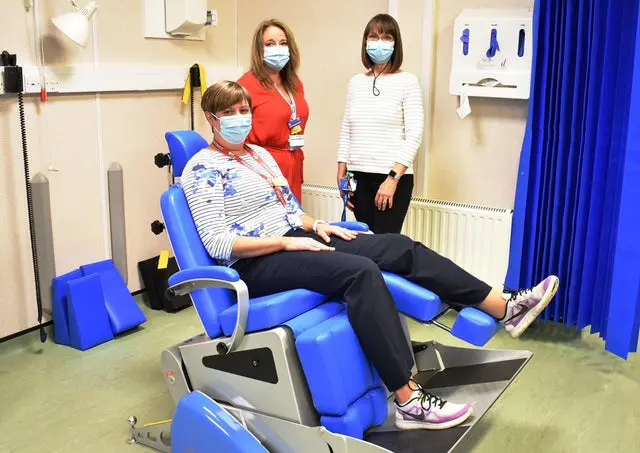 Patient sitting on podiatry chair with two personnel at the back